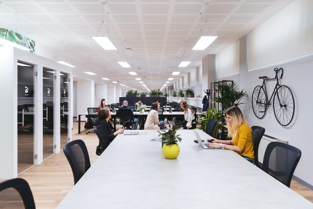 copernico PXilGoBofu8 unsplash 1 - Metro Offices A group of people are sitting at a table in a coworking space office.