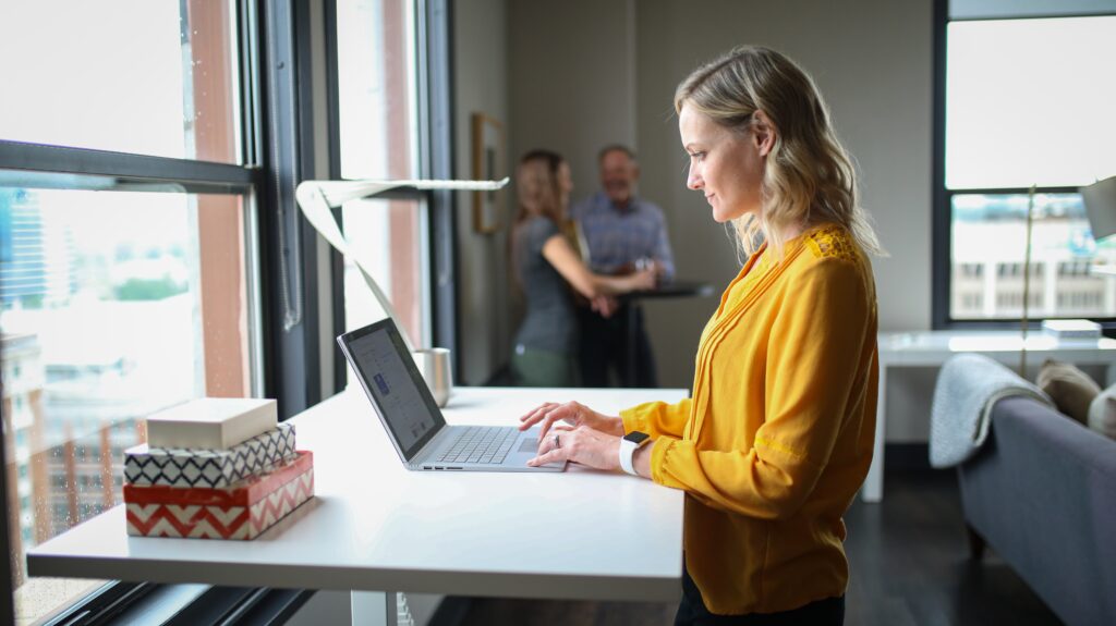 thestandingdesk 14HEl32 X2U unsplash - Metro Offices A woman using a laptop at a desk in a coworking space.