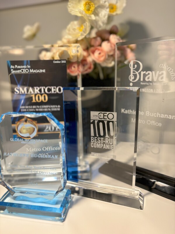 KB a few awards - Metro Offices A collection of corporate awards from Metro Offices on display with a floral arrangement in the background, celebrating achievements under the leadership of Kathlene Buchanan.