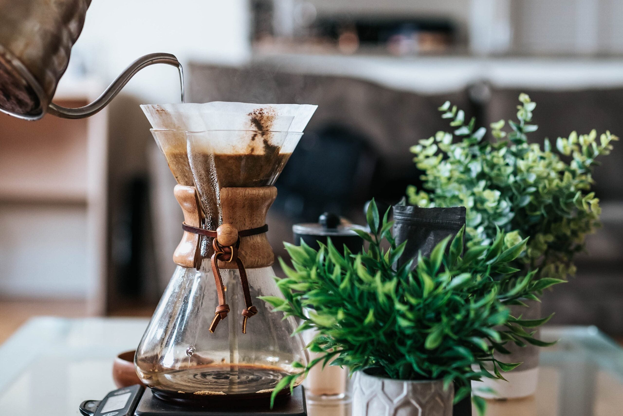 najib kalil BNHriM9hio4 unsplash edited 1 scaled - Metro Offices A person coworking at a shared workspace, pouring coffee into a glass coffee pot.