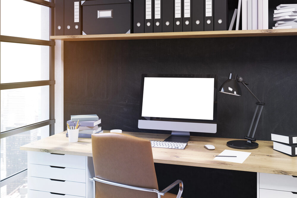 Metro Offices Offers Top Notch Workspace Solutions - Metro Offices A modern business office workspace with a computer, lamp, stacks of books, and files on a wooden desk—perfect for harnessing cloud computing to improve productivity—with shelves holding binders and boxes above.