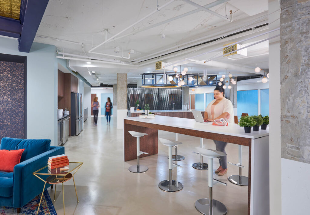 kitchen 2 - Metro Offices A woman sits at a coworking space bar.