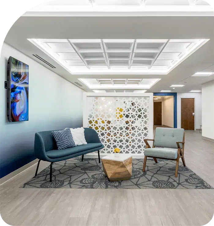 Suites Image 2024 - Metro Offices A lobby with blue chairs and paintings on the wall.