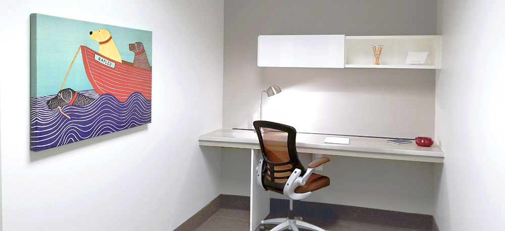 ?seraph accel gi=wp content%2Fuploads%2F2024%2F07%2F006 DO - Metro Offices Minimalist office with a desk, chair, and wall-mounted shelves. A colorful painting of dogs in a boat hangs on the wall.