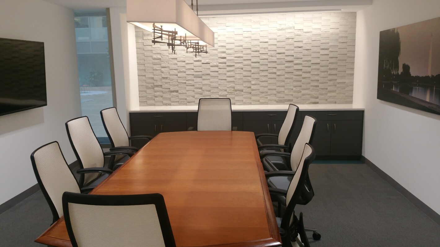 ?seraph accel gi=wp content%2Fuploads%2F2024%2F07%2F009 LC - Metro Offices A conference room with a wooden table, six chairs, a wall-mounted light fixture, a textured wall, and a window. A television is mounted on one wall, and a piece of framed art is on another.
