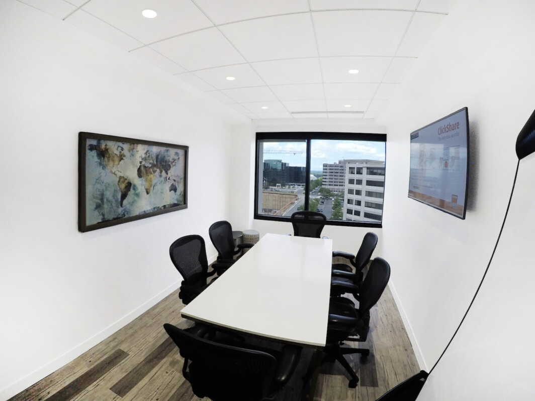 ?seraph accel gi=wp content%2Fuploads%2F2024%2F07%2F010 BR - Metro Offices Modern conference room with a rectangular table, black office chairs, a large window showcasing an urban view, wall art, and two mounted screens.