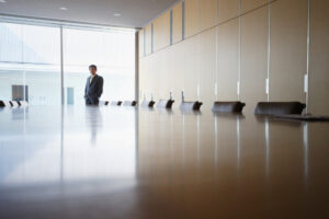 Boardroom - Metro Offices A person in business attire stands at the end of a long, empty conference table in a modern Washington DC meeting room with large windows, showcasing the professionalism of shared office spaces.