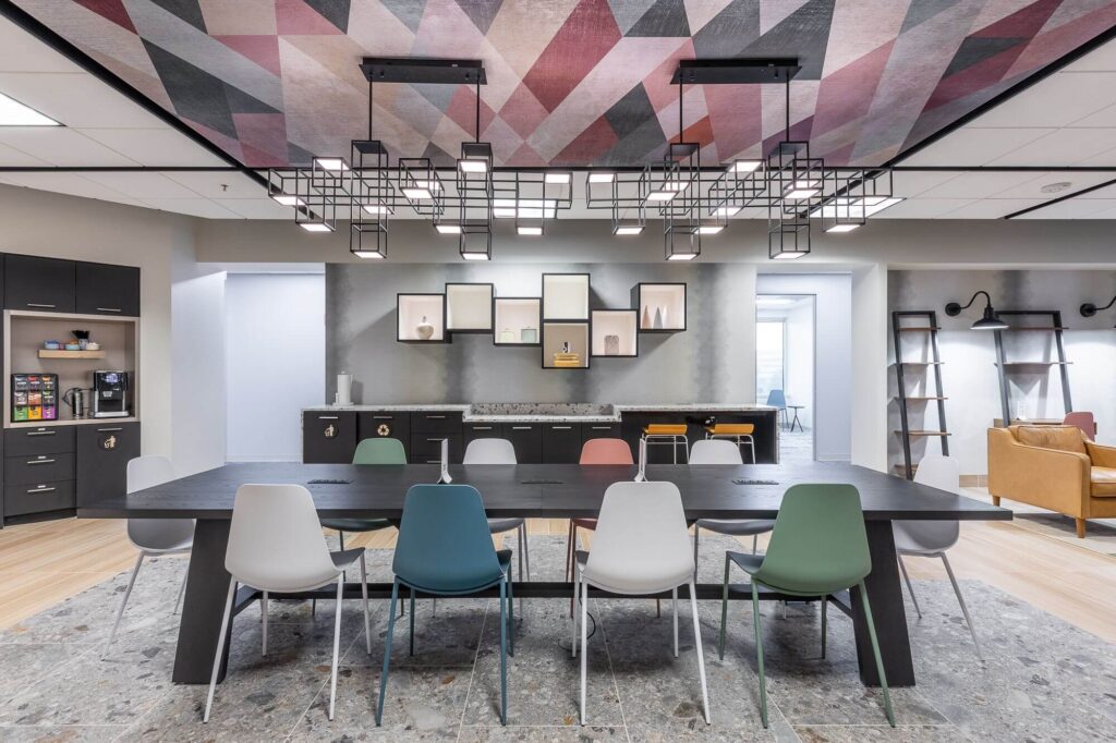 A vibrant coworking space furnished with a table and chairs, featuring a colorful ceiling design.