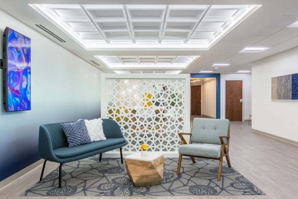 The lobby of a medical office is decorated with blue chairs and artwork in a coworking space setting.