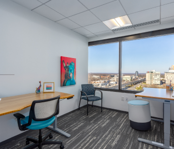 An office suite with two desks and a window overlooking a city.