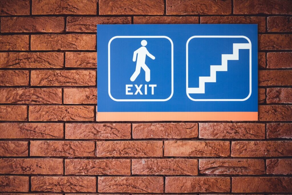 An exit sign near a workspace on a brick wall.